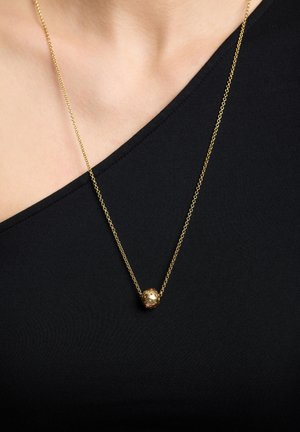 Collar de cadena de oro con un colgante esférico texturizado, que cuelga sobre una blusa negra. El colgante presenta un detalle intrincado, realzando su diseño.
