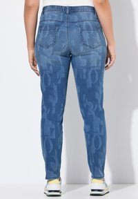 Džínové kalhoty v světle modré barvě se zesvětleným grafickým vzorem, elastickým pasem a dvěma zadními kapsami, navržené pro pohodlí.