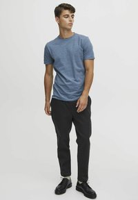 Blå bomull t-skjorte med rund hals, kombinert med svarte smale bukser og svarte snøresko. Enkel design med minimal detaljering.