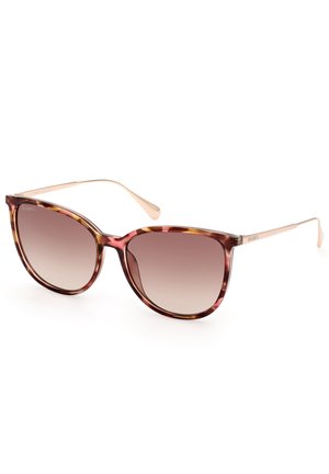 Lunettes de soleil écaille de tortue avec une large forme œil de chat. Verres dégradés marron et branches en métal doré avec des extrémités courbées.