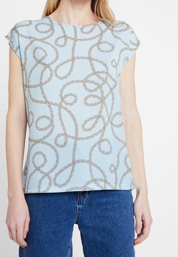 Top corto de manga corta en azul claro con un patrón de cadenas en dorado, con un corte holgado y textura suave. Combinado con pantalones de mezclilla.
