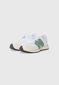 Baskets blanches avec un accent vert, fabriquées en matériau lisse et en daim. Elles présentent une languette gris clair et une semelle noire texturée.