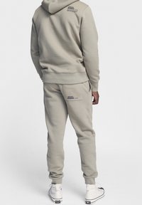 Set di felpa con cappuccio e pantaloni della tuta grigio chiaro, realizzato in morbido cotone. Presenta il logo sul retro e tasche laterali sui pantaloni.