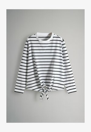 Camicia bianca a maniche lunghe con strisce orizzontali nere e dettaglio del nodo anteriore, realizzata in un tessuto morbido. Collo rotondo e design a vestibilità rilassata.