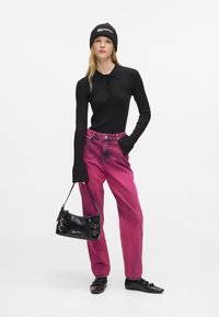 Crna rebrasta polo majica dugih rukava, ružičaste izbledele traperice visokog struka, crna torba s kopčama i crne balerinke. Jednostavna, ležerna odjeća.