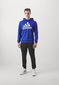 adidas Sportswear SPORTSWEAR HOODED TRACKSUIT SET - Tuta - semi lucid blue/black