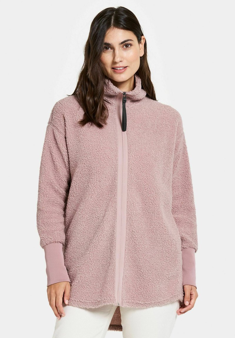 Flauschige rosa Fleece-Zip-Jacke mit hohem Kragen, gerippten Bündchen und einem kontrastierenden Reißverschluss. Weiche Textur und lässiger Schnitt.