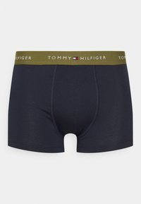 Temno modri bokseric s stretch tkanino, ki ima zelen elastičen pas z logotipom "TOMMY HILFIGER" in kontrastne šivane podrobnosti.