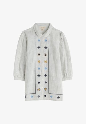 Svītrota bēškrāsas pogu kleita ar zilu, dzeltenu un melnu izšuvumu. Komplektā ir apkakle un bumbu formas piedurknes.