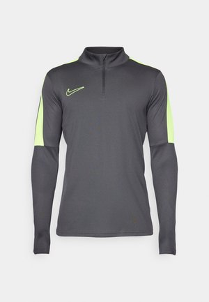 Maglietta sportiva grigia a maniche lunghe con colletto a mezza zip, con dettagli verde neon sulle spalle e sulle maniche, e un logo sul petto.