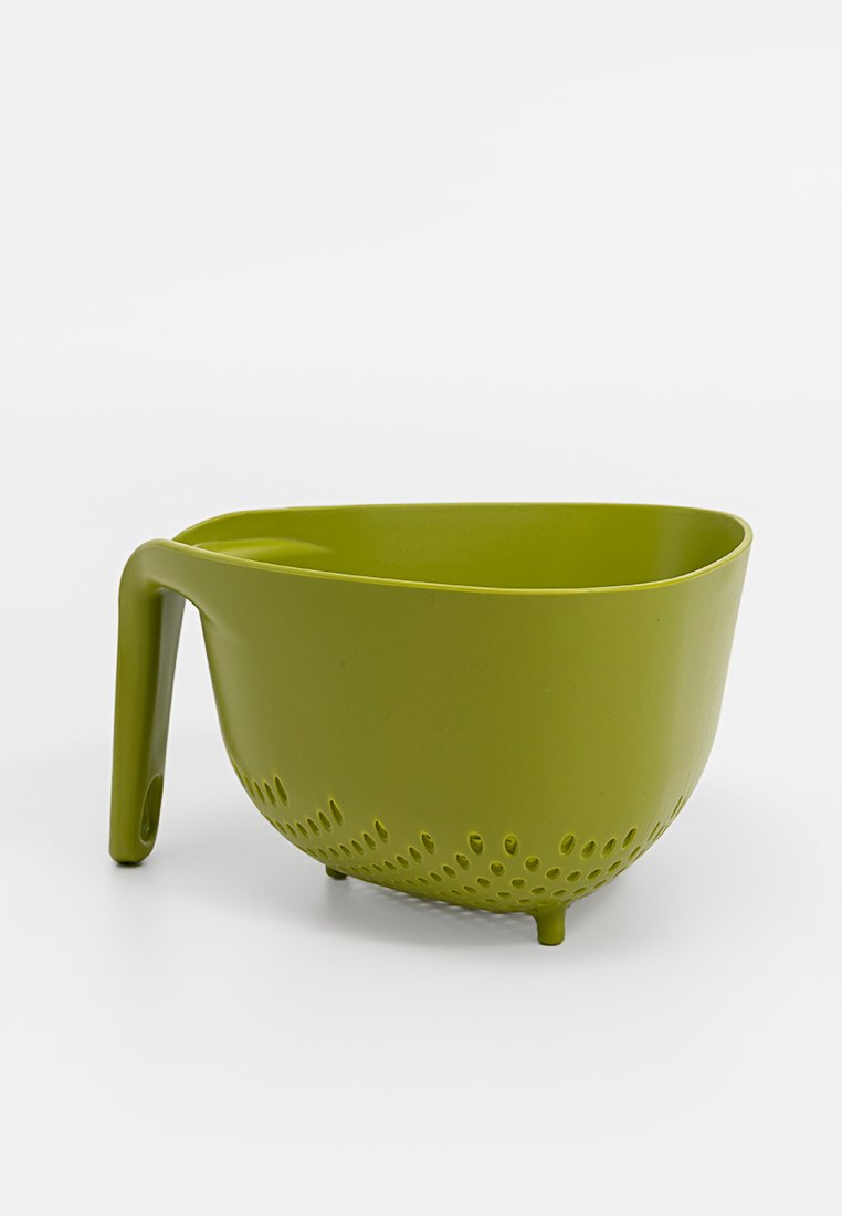 Colador de plástico verde con forma curva, mango integrado y pequeños orificios en la parte inferior para el drenaje. Textura suave y base estable.