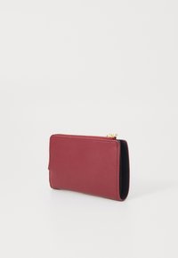 Portefeuille en cuir bordeaux avec une texture lisse, de forme rectangulaire, fermeture éclair et un intérieur noir contrastant. Design minimaliste.