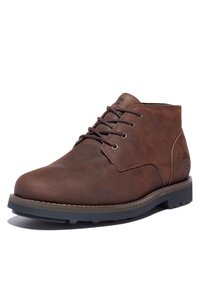 Botte chukka en cuir marron avec lacets, bout rond et finition texturée. Dispose d'œillets dorés et d'une semelle extérieure en caoutchouc avec un bord marron.