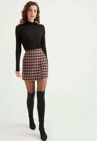 Schwarzes Langarmtop, kombiniert mit einem Minirock im pinken Hahnentrittmuster und schwarzen Overknee-Stiefeln, mit slim Fit und glatter Textur.