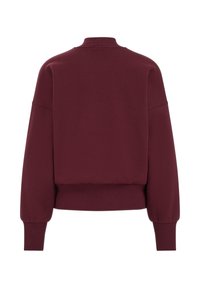 Pullover di colore bordeaux con colletto alto a costine, spalle cadenti e polsini aderenti. Tessuto morbido e vestibilità rilassata.