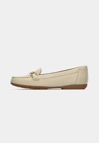 Beige leren loafers met een gouden gesp en stikseldetails, voorzien van een afgeronde neus en een gestructureerde rubberen zool voor grip.