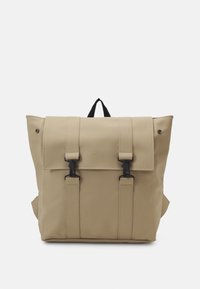 Sac à dos étanche beige en matériau lisse, doté d'une fermeture à rabat avec deux clips noirs et d'une poignée supérieure. Design minimaliste.