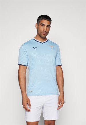 Maglia da calcio azzurro chiaro a maniche corte, con un motivo testurizzato, colletto blu navy e logo del club. Pantaloni corti bianchi completano l'outfit.