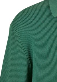 Grüner gerippter Strickpullover mit Kragen, einer strukturierten Oberfläche und taillierten Ärmeln, die ein strukturiertes Aussehen und Gefühl betonen.