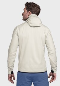 Leichte, cremefarbene Kapuzenjacke mit taillierter Passform, verstellbarer Kapuze und kontrastierenden schwarzen Akzenten. Glatte Textur und sportlicher Schnitt.