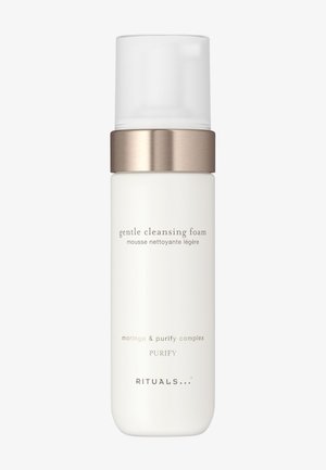 Weiße Flasche des Rituals sanften Reinigungsschaums mit goldenem Band und transparentem Pumpdeckel vor hellem Hintergrund.