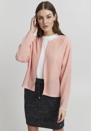 Lichtroze, open voorkardigan van een textuurstof, met lange mouwen en een afgeronde zoom, gecombineerd met een witte top en een donkergrijze rok met trekkoord.