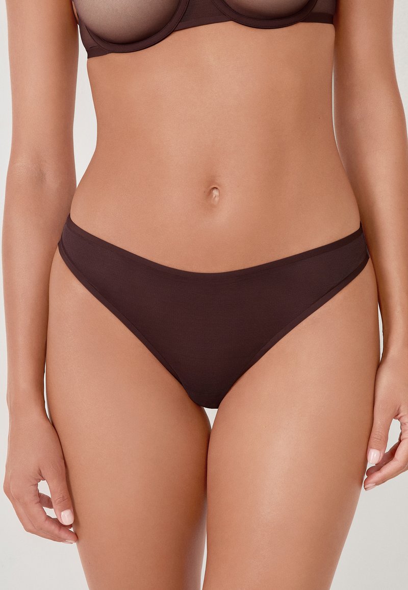 Bas de bikini marron en tissu lisse. Présente un design taille basse avec des côtés étroits et une couverture minimale, sans matériel ni motifs visibles.