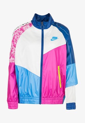 Barevná větrovka s částmi v růžové, bílé, modré a fialové barvě, s předním zipem, vysokým límcem a síťovanými detaily.