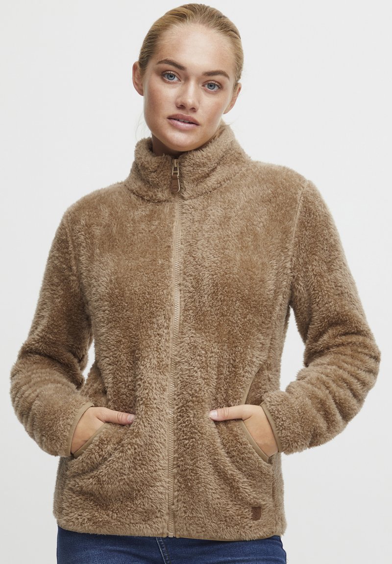 Brown fleece jacket with high collar, front zipper, side pockets, and textured fabric. Designed for warmth and comfort.