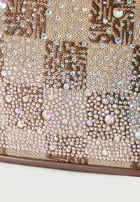 Κοντινό πλάνο καφέ υφάσματος με περίτεχνη κεντητή λουλουδάτη διακόσμηση και πολύχρωμες διακοσμήσεις από ρητίνες σε διάφορα μεγέθη.