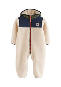 Combinaison bébé en polaire couleur crème avec empiècements bleu marine aux épaules, doublure verte à la capuche, fermeture éclair rouge à l'avant et petite écusson sur la poitrine.