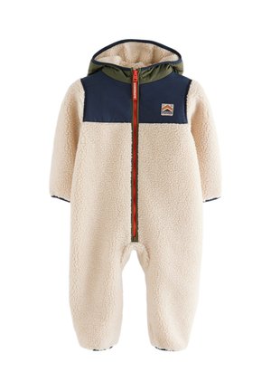 Enfant portant une veste sherpa polaire crème avec des panneaux d’épaule bleu marine et verts et une fermeture éclair rouge avec le logo Superdry.