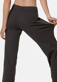 Pantaloni a gamba larga grigi a costine con vita elastica. Il tessuto appare morbido e elasticizzato, con un design aderente attorno alla vita e ai fianchi.