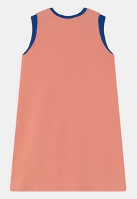 Um vestido sem mangas em tecido coral com um corte descontraído, apresentando um decote canelado em azul-marinho. Textura suave, design simples, sem adornos.