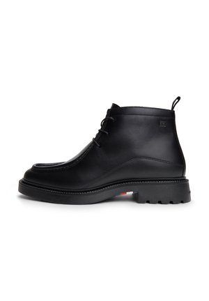 Bottine en cuir noir à lacets sur l'avant, bout arrondi, semelle épaisse à crampons, et languette au talon, vue de côté extérieur.