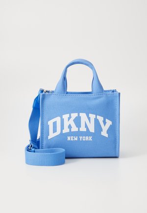 Niebieska torba z płótna z dwiema górnymi uchwytami i regulowanym paskiem. Zawiera białe napisy "DKNY NEW YORK" z przodu. Prostokątny kształt.