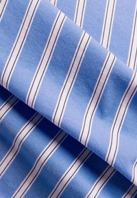 Tessuto blu chiaro con strisce bianche e nere, caratterizzato da una consistenza liscia e un aspetto piegato, che mostra chiaramente il motivo.