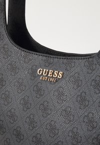 Borsa a tracolla nera in materiale sintetico con superficie testurizzata, placca logo dorata e motivo in rilievo. Design della tracolla curvata.