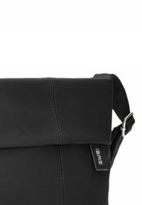 Borsa a spalla in pelle nera con pattina pieghevole, cuciture visibili, tracolla regolabile e dettagli in metallo argentato.