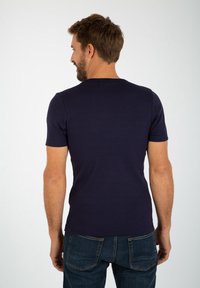T-shirt blu navy a maniche corte in cotone, con scollatura rotonda e texture liscia. Indossato con jeans in denim scuro.