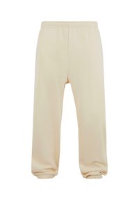 Pantalones de chándal beige con cintura elástica y puños elásticos, de corte holgado y tela suave, exhibidos sobre un fondo blanco.