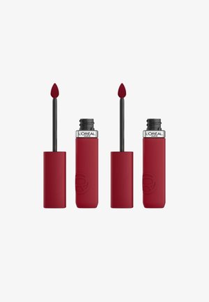 Produit à lèvres rouge avec une finition mate. Dispose d'un applicateur conique et d'un tube cylindrique à toucher doux, avec un logo en relief visible.