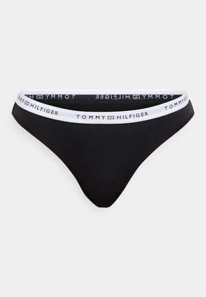 Μαύρο μπικίνι κάτω μέρος με λευκή ελαστική μέση που φέρει το λογότυπο "TOMMY HILFIGER". Μαλακό ύφασμα με λεία υφή και σχέδιο στρινγκ.