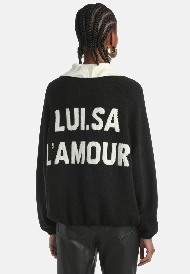 Liels melns džemperis ar baltu grafisku tekstu "LUI.SA L'AMOUR" mugurā, ar kontrastējošu baltu apkakli un adīšanas tekstūru.
