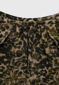 Jaguarprint stof med en lille hvid knaplukning ved halsen og en lodret slids under knappen.
