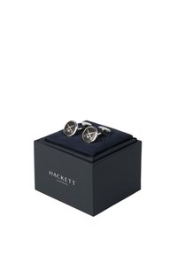 Cuflinkovi u srebrnoj boji sa okruglim crnim emajliranim licem s bijelim dizajnom, predstavljeni u tamnoplavoj kutiji s mekanim unutarnjim oblogom.