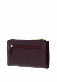 Portefeuille zippé bordeaux avec une surface texturée, doté d'une fermeture éclair dorée, d'une poche zippée à l'arrière et d'une forme rectangulaire élégante.