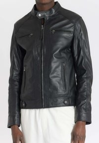 Veste en cuir noir avec un col montant, poches zippées, texture lisse et design ajusté, avec des accents en métal argenté.