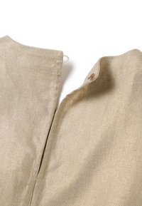 Tissu en lin beige avec une surface texturée, présentant une ouverture partielle avec un petit bouton et un détail de boucle au niveau du col.