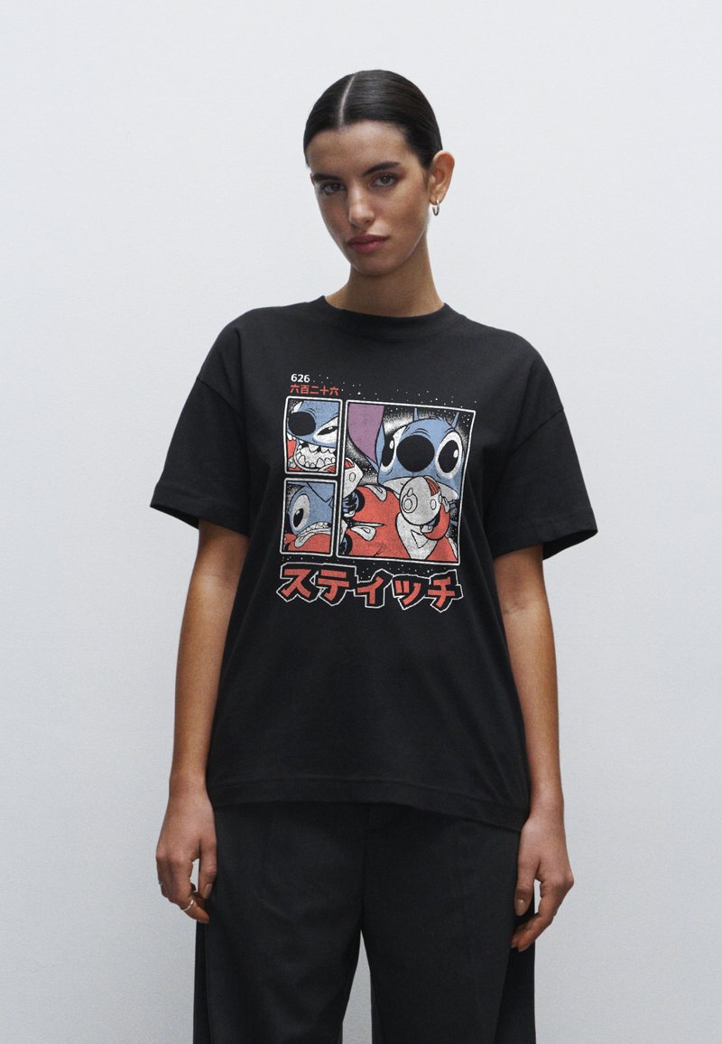 Sort bomulds T-shirt med et grafisk print af animerede figurer. Korte ærmer, afslappet pasform og bemærkelsesværdig japansk tekst i rød.